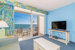 a living room with a television and a balcony with the ocean at Spacious 1 BR Condo-Breathtaking Oceanfront Views! Bay Watch 706 in Myrtle Beach