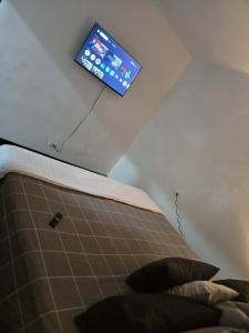 Un televisor colgado en el techo de un dormitorio. en Alquiler de habitaciones en CARACAS, en Caracas