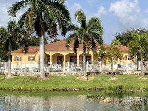Pine ManorResidence Condo II的水边有一栋黄色房子，周围种着棕榈树。