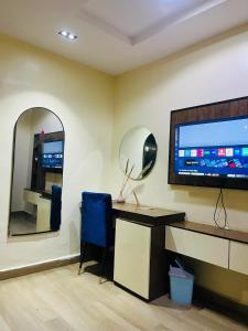 een kamer met een bureau, een televisie en een spiegel bij The Majj Hotel Sapele in Sapele