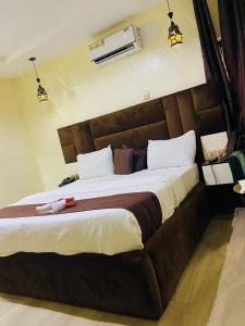 een slaapkamer met een groot bed met een bruin hoofdeinde bij The Majj Hotel Sapele in Sapele