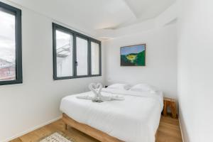 ein weißes Schlafzimmer mit einem Bett und zwei Fenstern in der Unterkunft Designer loft 5 minutes from Paris in Bagnolet