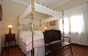 1 dormitorio con cama con dosel y silla en Solar De La Plaza en Salta