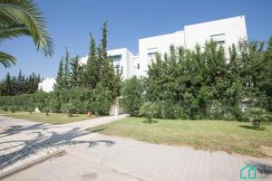 a large white building with trees in front of it at Le Premium Central luxueux et très confortable in Dār Şāliḩ Bey