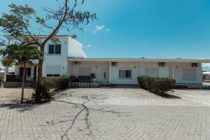 a white building with a tree in front of it at Smile Homes in Zanzibar City