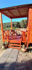 eine Holzterrasse mit zwei Stühlen und einer Bank in der Unterkunft Tiny house los cuchi in Hipólito Yrigoyen