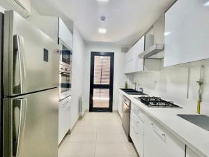 a kitchen with white counters and a stainless steel refrigerator at NEW bright and luxurious 2 bedrooms in Rd Malaga in Sidi Daoud