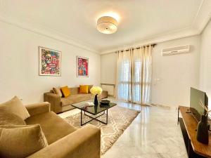 a living room with a couch and a table at Safran II Appartement très central avec Terrasse à la Marsa in Dar el Ouzir