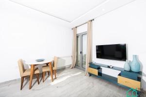a living room with a table and a tv at New 1 bedroom with swimming pool next to Lac 2 in El Aouina Station