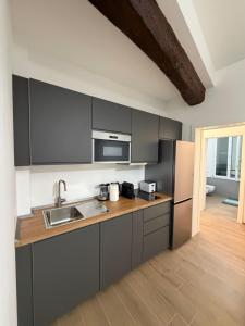 Una cocina con gabinetes negros y un refrigerador de acero inoxidable. en Adriano Space, en Módena