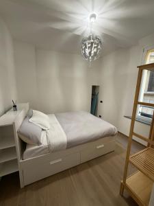 Habitación blanca con cama y lámpara de araña. en Adriano Space, en Módena