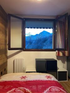 Schlafzimmer mit einem großen Fenster und einem roten Bett in der Unterkunft Appartement cosy quartier Napoléon in Val Cenis