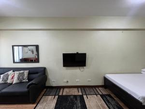 a bedroom with a couch and a tv on the wall at Cozy Staycation at Eastbay Residences in Manila