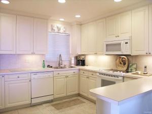 una cucina bianca con mobili bianchi e un forno a microonde di Oceanfront Three-Bedroom Apartment with Panoramic Views a Beverley Beach