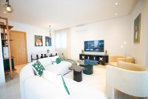 a living room with white furniture and a tv at Villa Apollon: Seaside and luxurious in El Haouach
