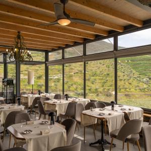 a dining room with tables and chairs and windows at Quinta do Tedo in Folgosa