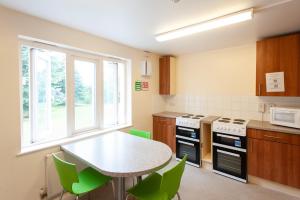 een keuken met een tafel en groene stoelen bij Villas at Park Campus in Cheltenham