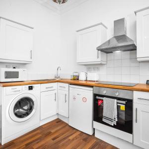 a kitchen with white cabinets and a washer and dryer at Stylish Apartment - Wolverhampton - Fast Wi-Fi - Parking 9PC in Wolverhampton