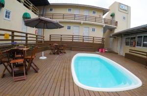 a pool on a deck with a table and an umbrella at Porto Pousada in Imbituba