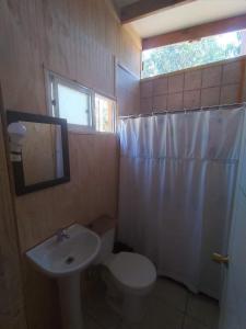 a bathroom with a sink and a toilet and a window at Cabañas Entre Bosques De Algarrobo in Algarrobo