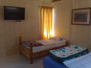 a bedroom with two beds and a tv and a window at Cabañas Entre Bosques De Algarrobo in Algarrobo