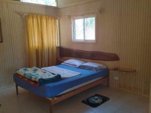 a bedroom with a bed with blue sheets and a window at Cabañas Entre Bosques De Algarrobo in Algarrobo