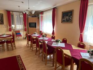 een eetkamer met tafels en stoelen en rode gordijnen bij Herkules Panzió in Nagykanizsa