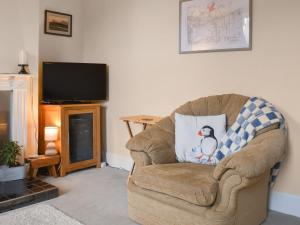 ein Wohnzimmer mit einem Sessel mit einem Pinguinkissen in der Unterkunft Ratcliffe Cottage in Ipswich