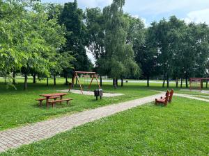 een park met bankjes en een schommel in het gras bij Herkules Panzió in Nagykanizsa