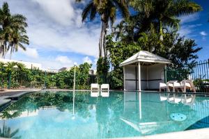 a swimming pool with chairs and a gazebo at Bundaberg International Motor Inn in Bundaberg