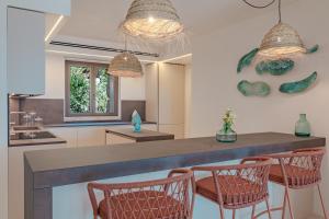 a kitchen with a bar with chairs and lights at La Tiara di Cervo in Liscia di Vacca
