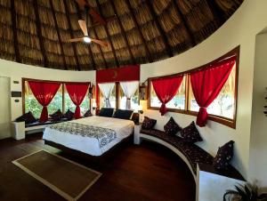 a bedroom with a bed with red curtains and a ceiling at Palapa Ix-Chel - Unique bungalow in San Ignacio