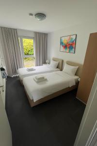 a hotel room with two beds and a window at Work & Travel Lodge Münsingen in Münsingen