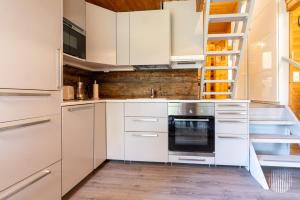 a kitchen with white cabinets and an oven at HilleVilla by Holiday in Lapland in Ylläsjärvi