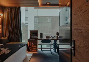 um quarto de hotel com uma cama, uma escrivaninha e uma janela em The Click Clack Hotel Bogotá em Bogotá