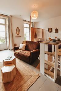 een woonkamer met een bruine leren bank en een tafel bij Le Cocon Carmel by CozyLife in Niort