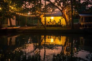 a night view of a house with lights over a body of water at Lakefront 1 BR Cabin with Lake access & Hammock in Kollam +12 photos