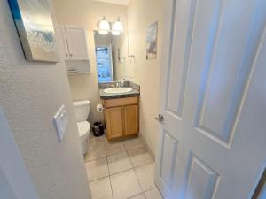 ein Bad mit einem Waschbecken, einem WC und einer Tür in der Unterkunft 2 Bedroom Condo in the Heart of Rockaway Beach in Rockaway Beach