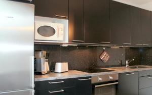 une cuisine avec des armoires noires et un four micro-ondes dans l'établissement Convenient Apartment for 3 in Varissuo, à Littoinen