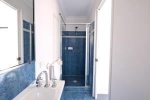 Coastal 2BR Retreat Heart of Broadbeach Living في غولد كوست: حمام مع حوض ودش ذو بلاط ازرق