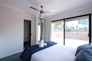 Coastal 2BR Retreat Heart of Broadbeach Living في غولد كوست: غرفة نوم بسرير ابيض عليها دبدوب