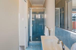 Modern 2BR Apartment Beach and Dining in Broadbeach في غولد كوست: حمام مع حوض استحمام ودش ذو بلاط ازرق +29 صورة