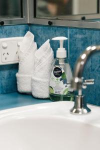 Modern 2BR Apartment Beach and Dining in Broadbeach في غولد كوست: حوض مع زجاجة من صابون اليد والمناشف