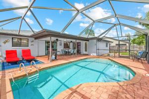 a swimming pool with two red chairs and a house at Florida Flair Villa in Cape Coral Hospital Heliport