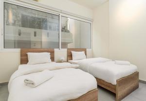 two beds with white sheets and towels on them in a room at Curl 2-Bedroom Apartment in Gemmayzeh in Ar Rumayl