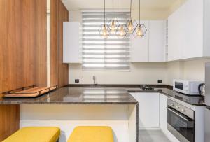 a kitchen with white cabinets and a granite counter top at Curl 2-Bedroom Apartment in Gemmayzeh in Ar Rumayl