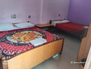 dos camas en una habitación con dos mesas y una cama sidx sidx sidx en Srusti Residency Mysore, en Jāmb