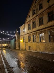 an empty street at night with a building and lights at Vecpilsētas apartaments in Cēsis