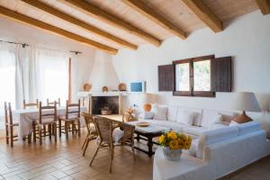 una sala de estar con un sofá, una mesa y sillas en Finca Fiori 2, en Is Molas 