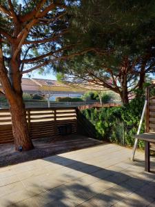 a bench sitting next to a tree and a bridge at Maison au pin in Narbonne-Plage